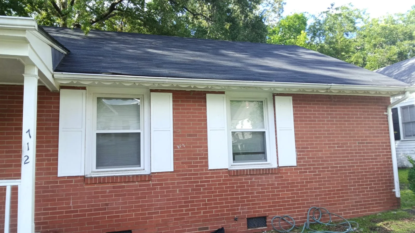 Brick ranch house with a dark shingle roof, fresh white trim and shutters